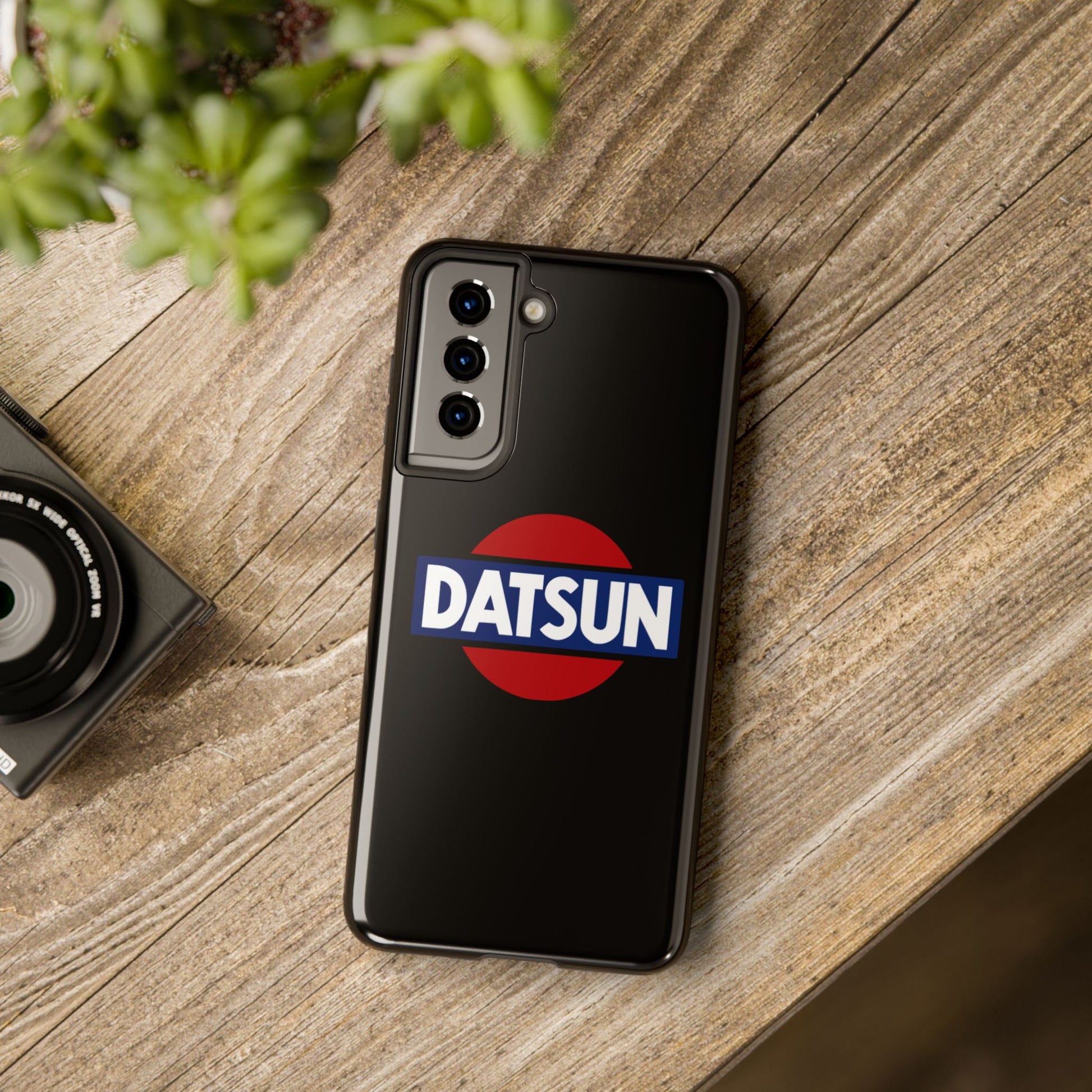 Black Samsung Galaxy S21 Datsun phone case on a table with accessories.