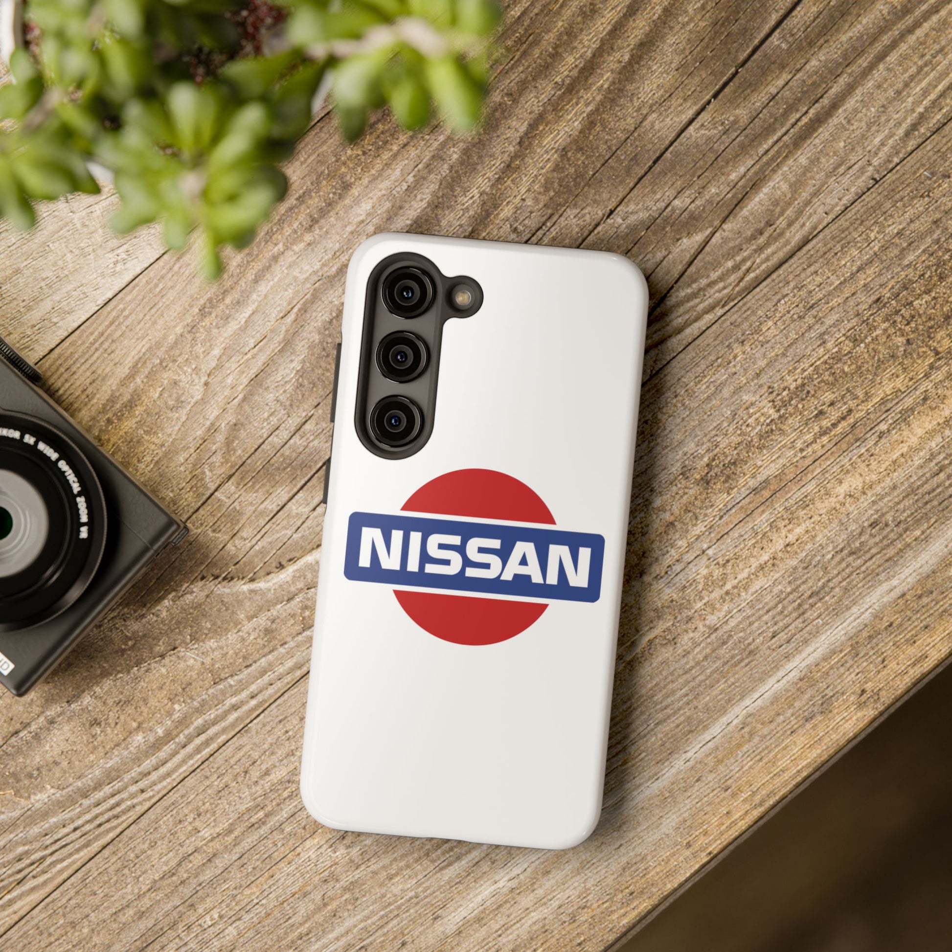 White Samsung Galaxy S23 Vintage Nissan phone case on a table with accessories.