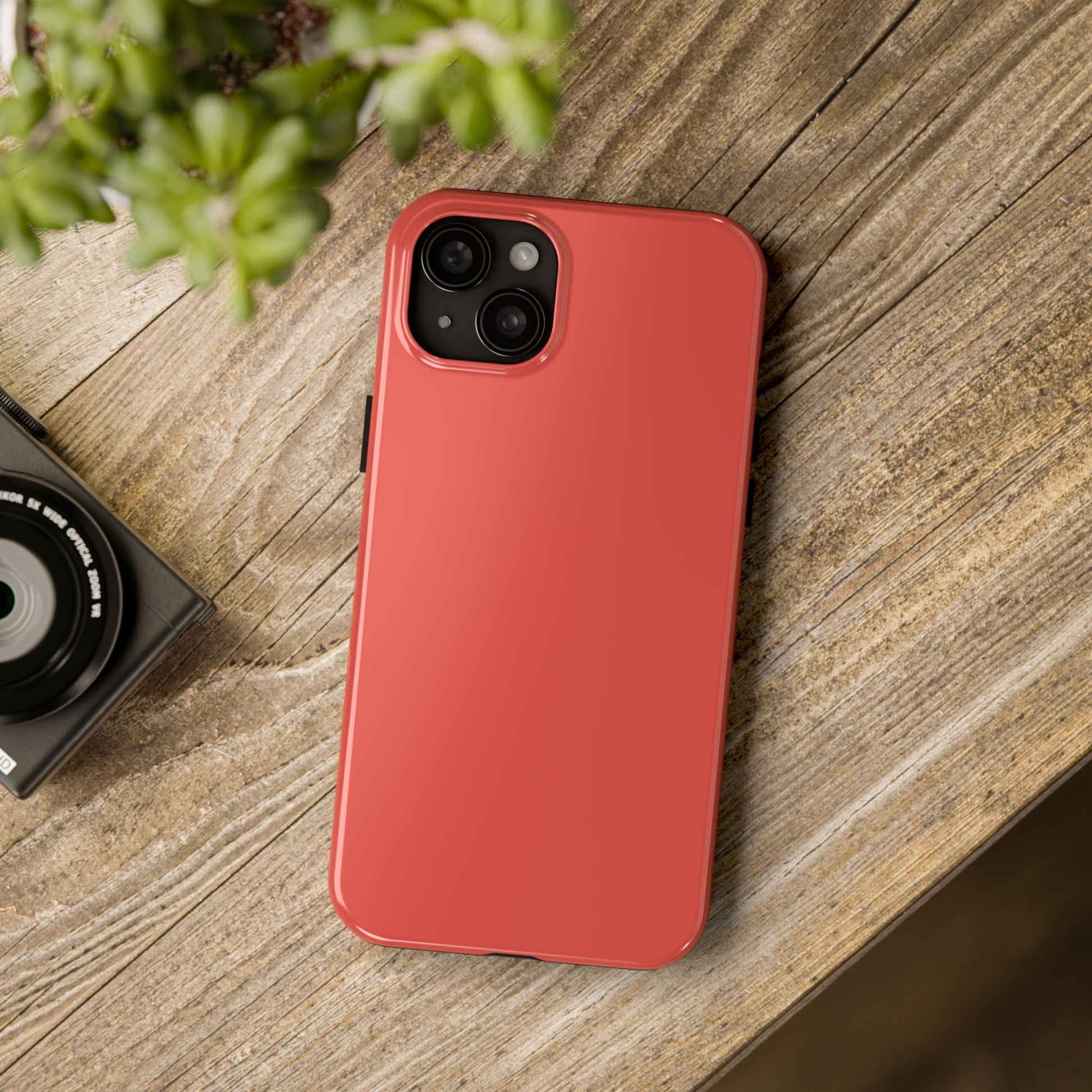 iPhone 15 Plus BMW Sakhir Orange phone case on a table with accessories. 