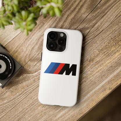 White iPhone 15 Pro BMW M phone case on a table with accessories.