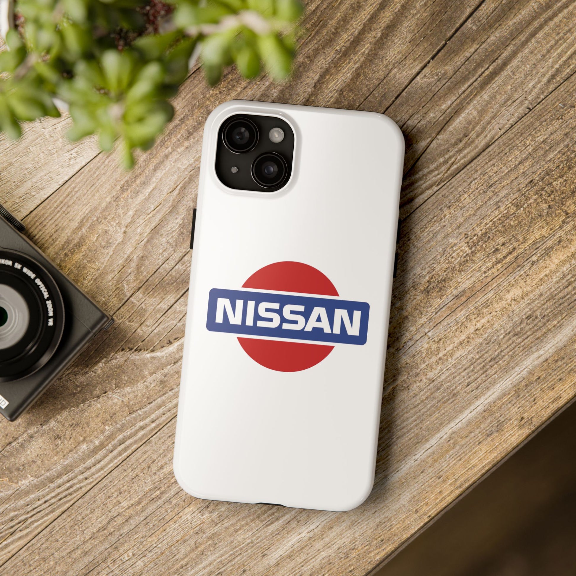 White iPhone 15 Plus Vintage Nissan phone case on a table with accessories.