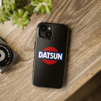 Black iPhone 15 Datsun phone case on a table with accessories.