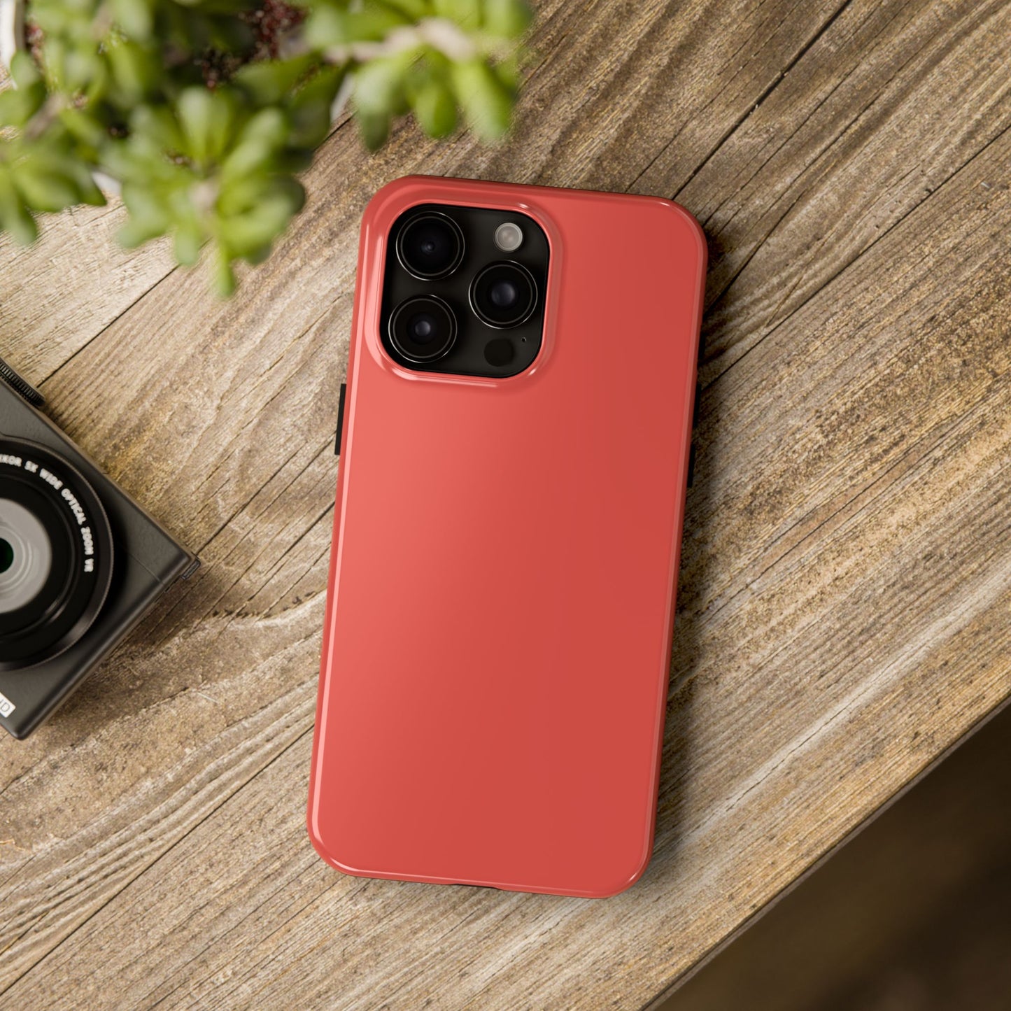 iPhone 15 Pro Max BMW Sakhir Orange phone case on a table with accessories. 