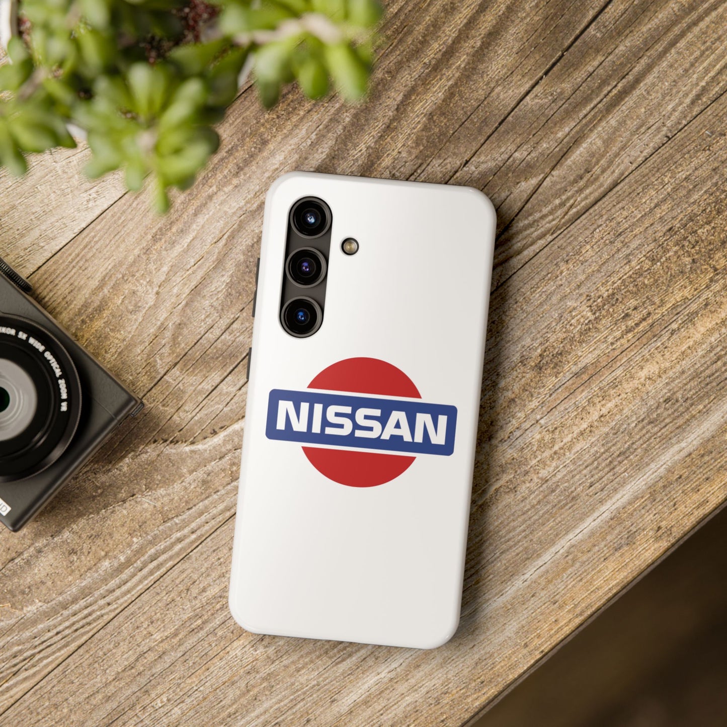 White Samsung Galaxy S24 Vintage Nissan phone case on a table with accessories.