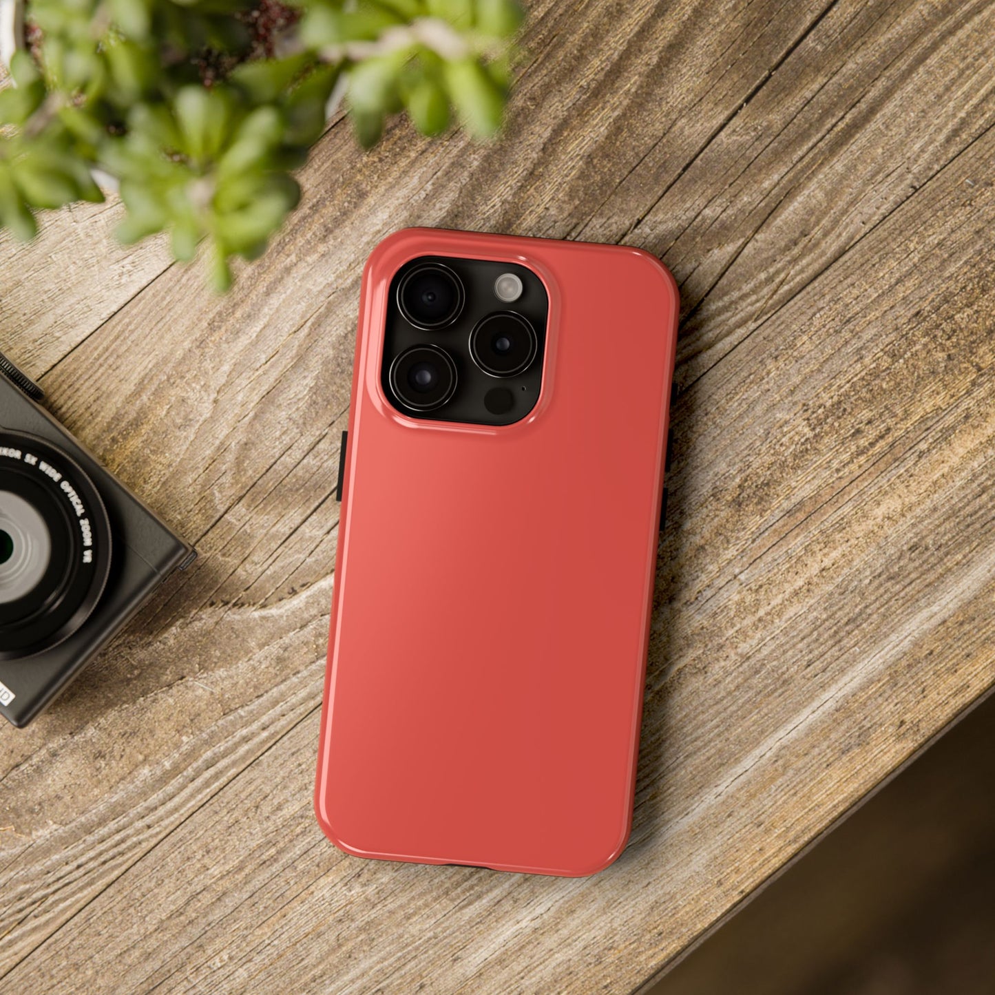 iPhone 15 Pro BMW Sakhir Orange phone case on a table with accessories. 