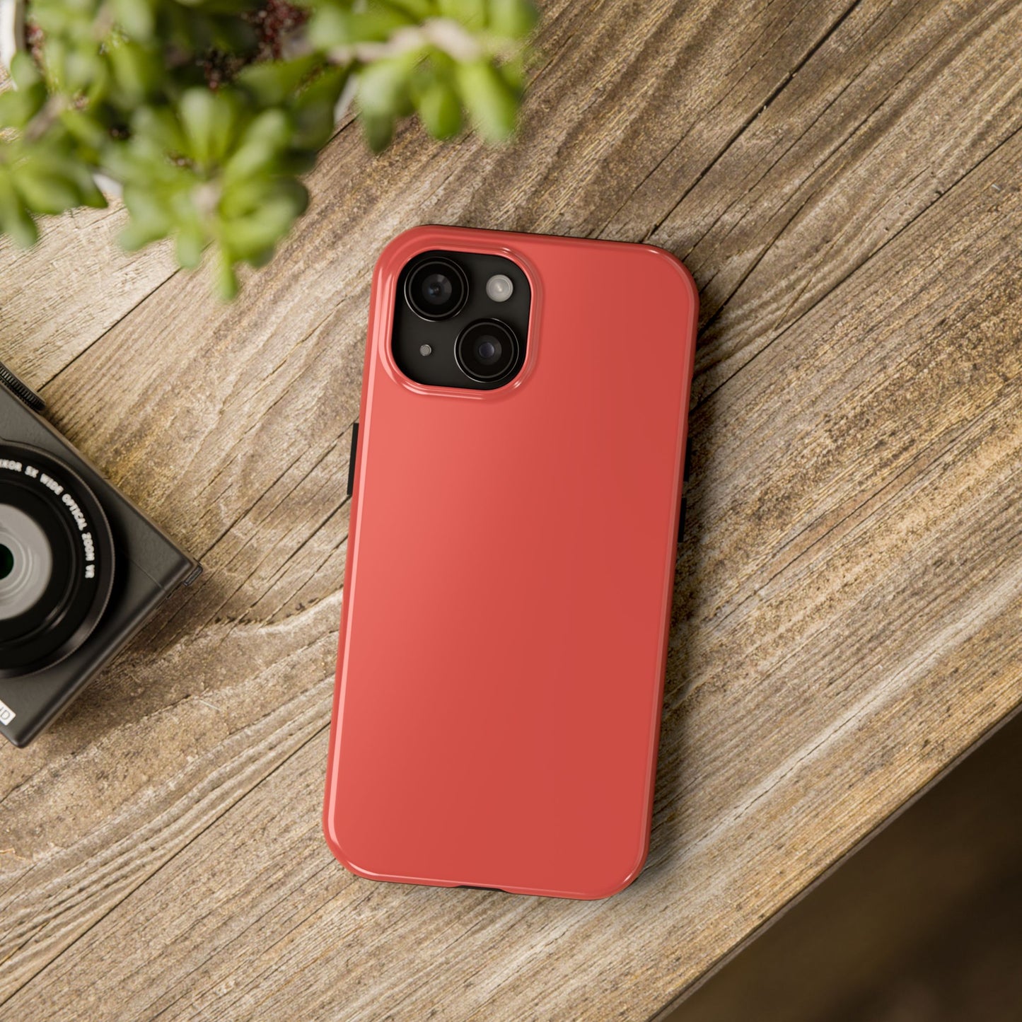 iPhone 15 BMW Sakhir Orange phone case on a table with accessories. 