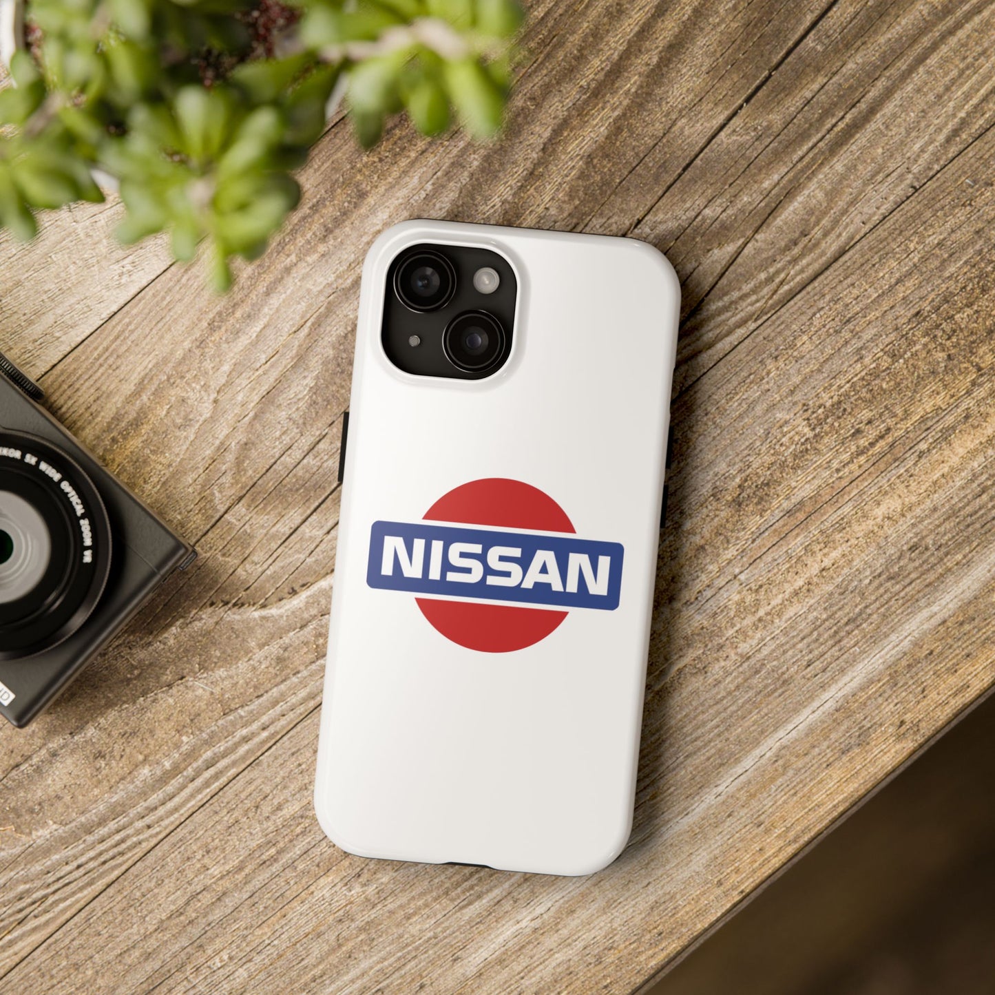 White iPhone 15 Vintage Nissan phone case on a table with accessories.