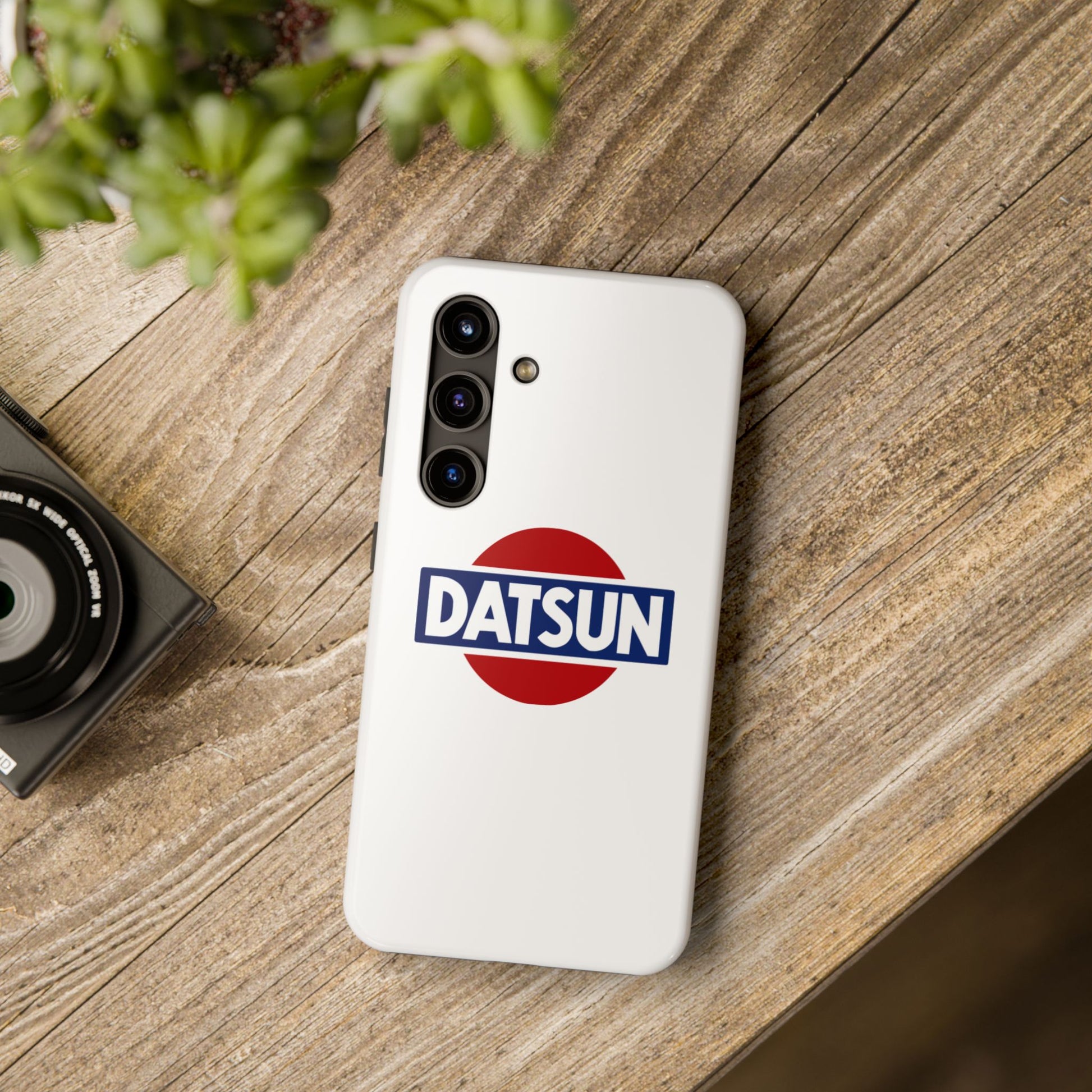 White Samsung Galaxy S24 Datsun phone case on a table with accessories.