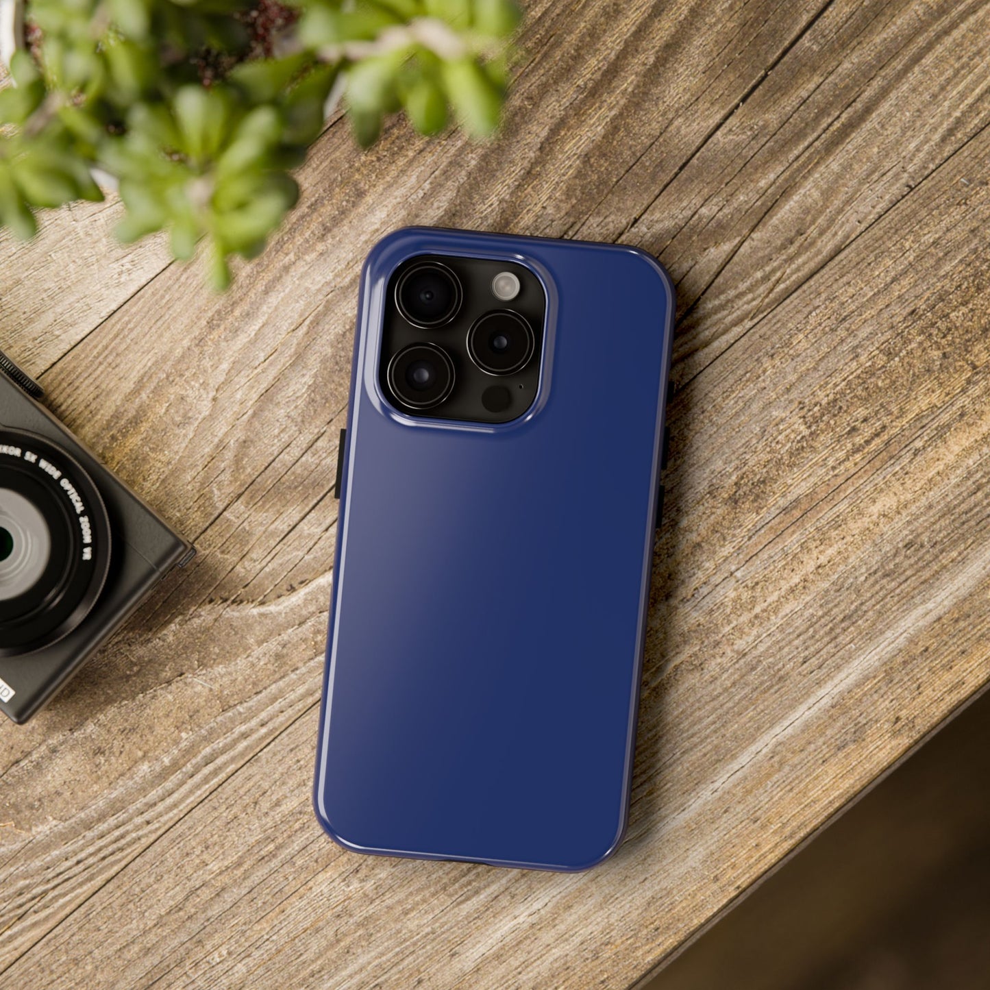 iPhone 15 Pro BMW Tanzanite Blue phone case on a table with accessories. 