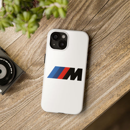 White iPhone 15 BMW M phone case on a table with accessories.