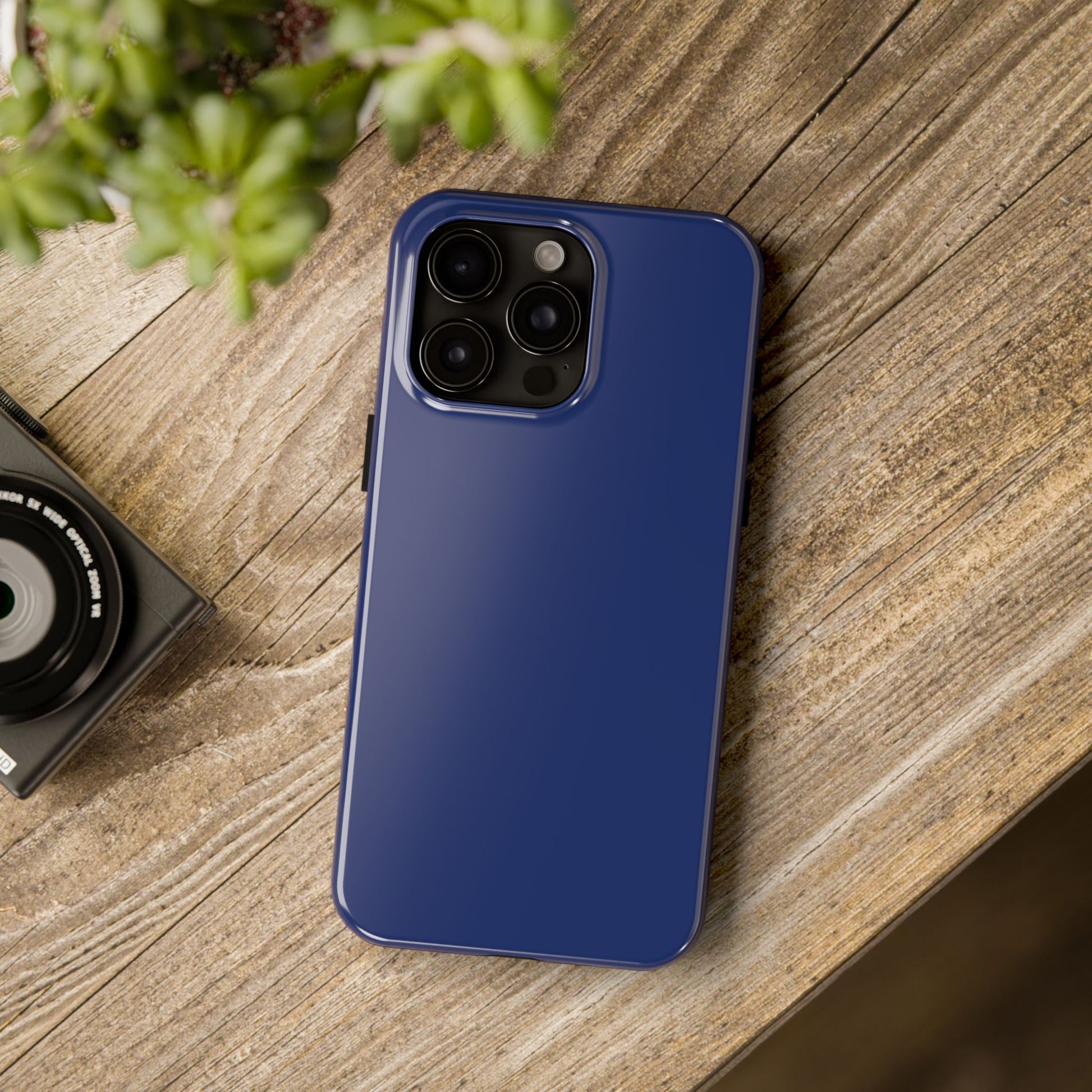 iPhone 15 Pro Max BMW Tanzanite Blue phone case on a table with accessories. 