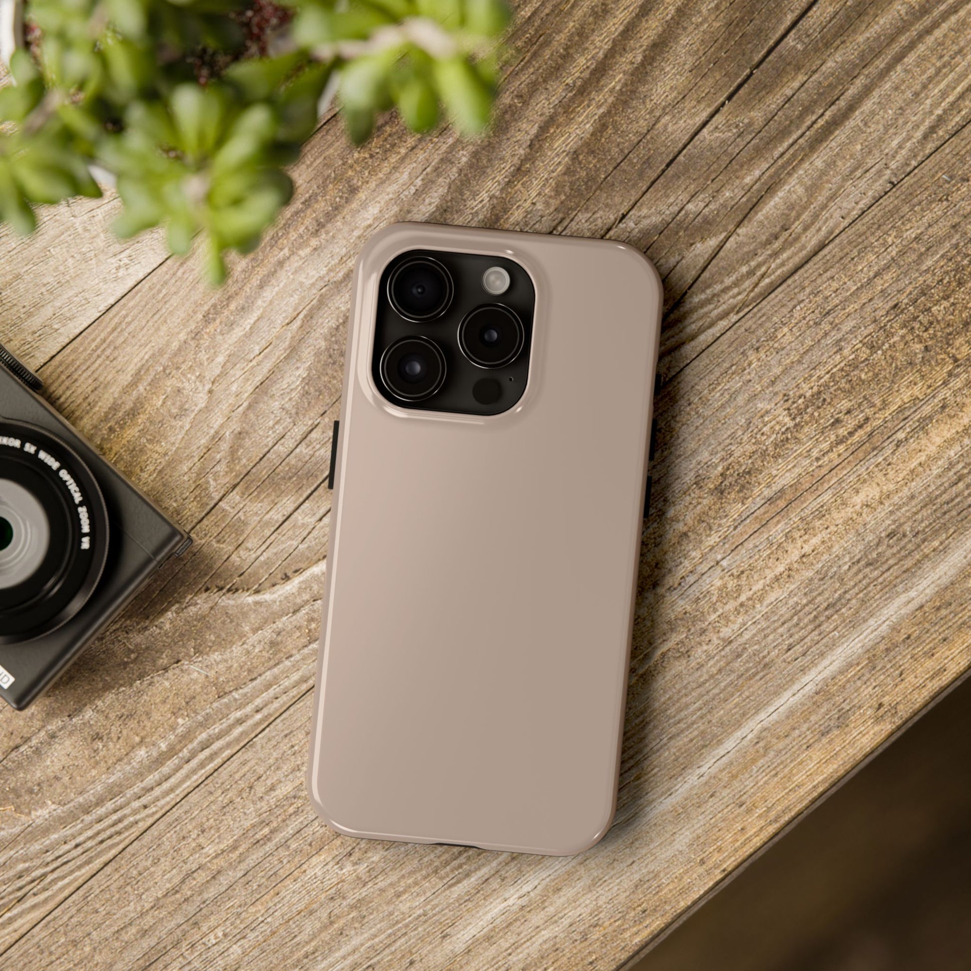 iPhone 15 Pro Aston Martin Arizona Bronze phone case on a table with accessories. 