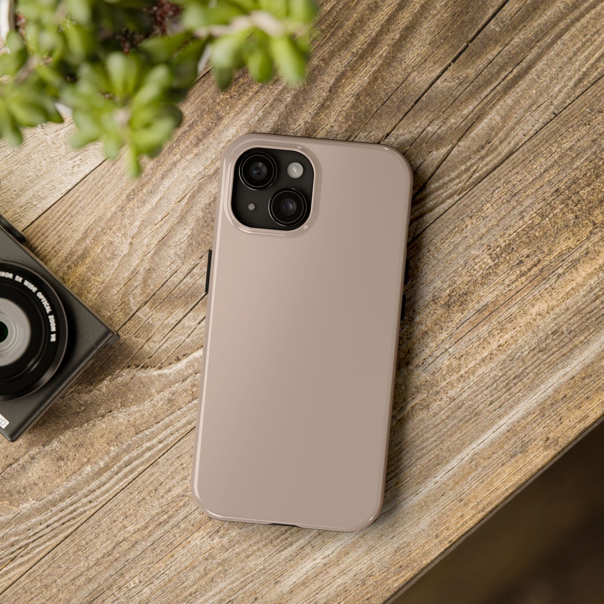 iPhone 15 Aston Martin Arizona Bronze phone case on a table with accessories. 