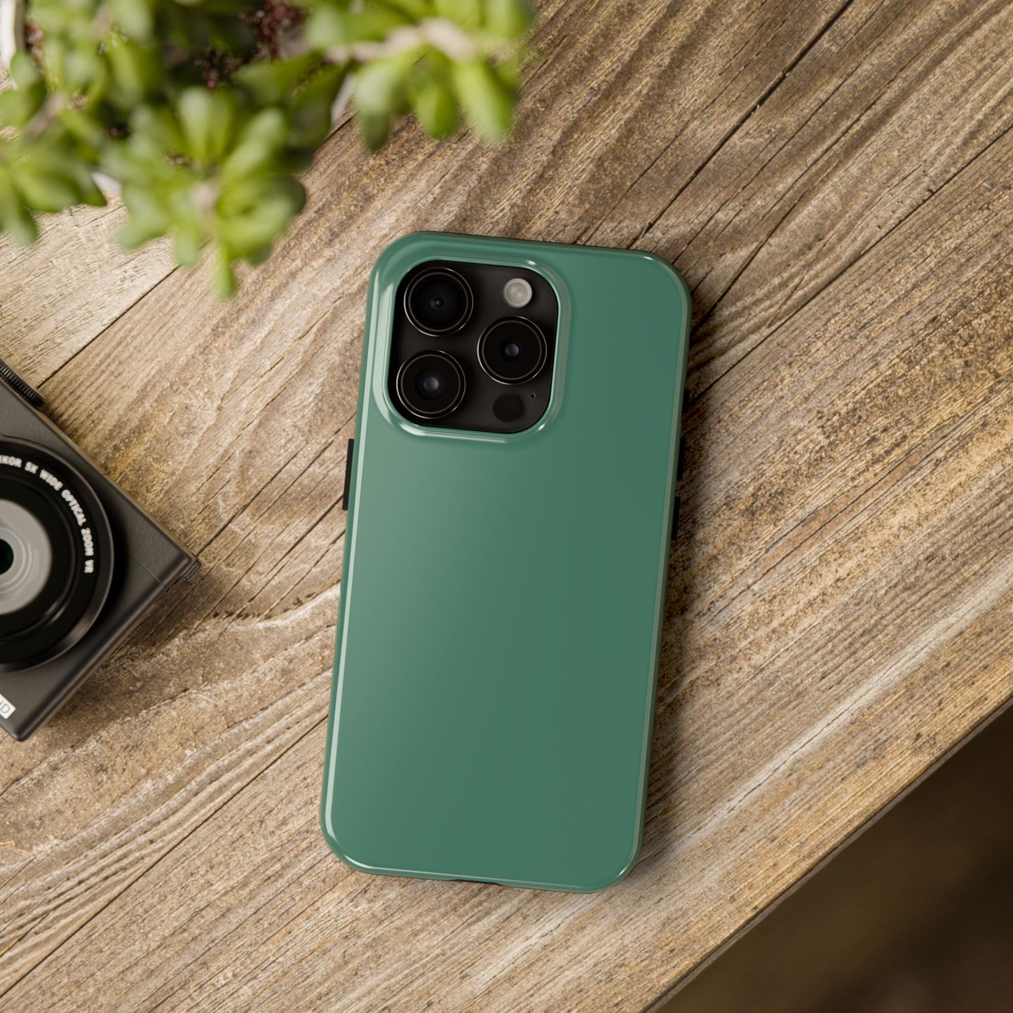 iPhone 15 Pro Aston Martin Racing Green phone case on a table with accessories. 