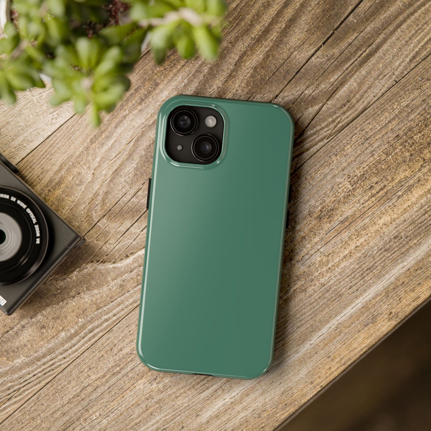 iPhone 15 Aston Martin Racing Green phone case on a table with accessories. 