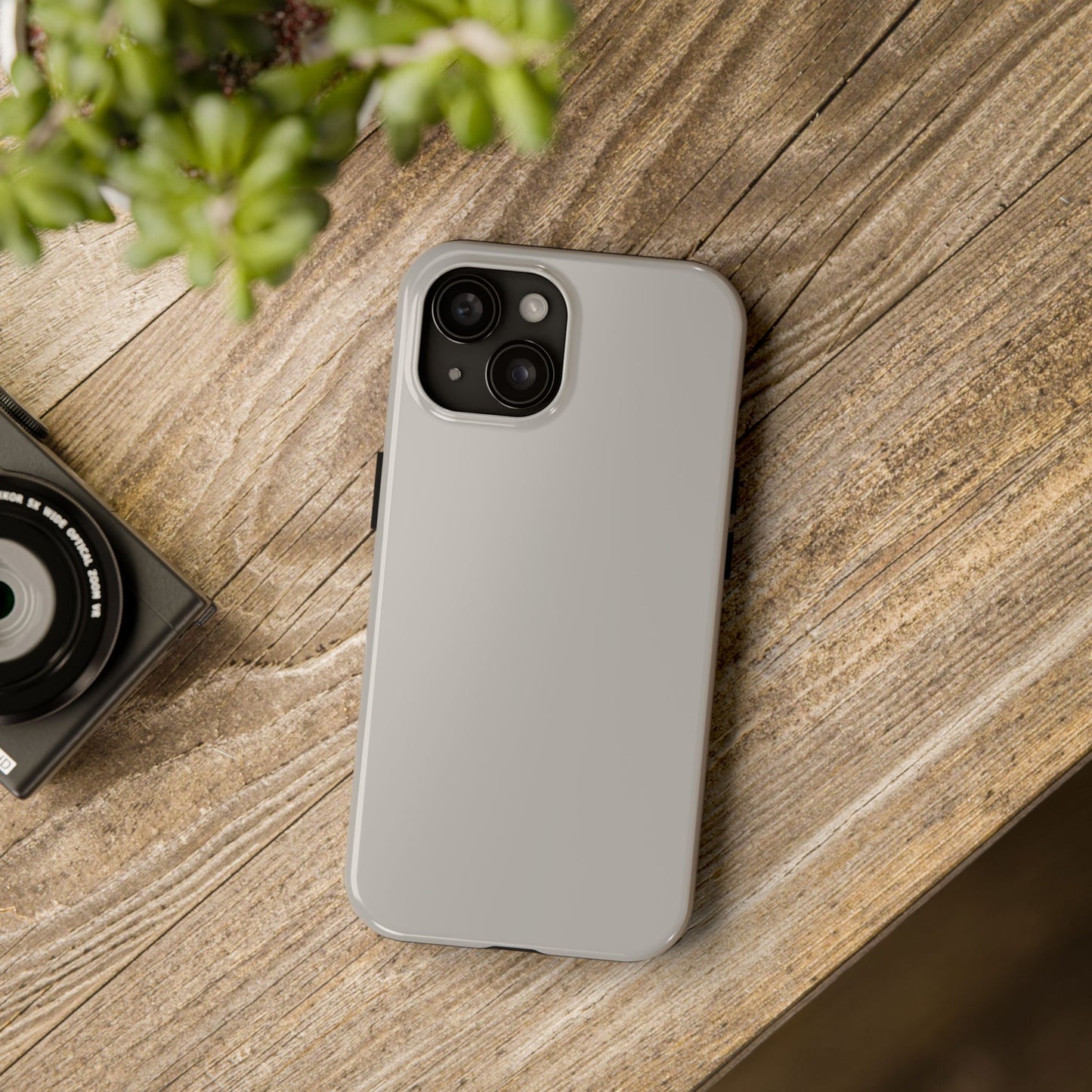 iPhone 15 Aston Martin Silver Birch phone case on a table with accessories. 