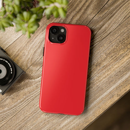 iPhone 15 Plus Aston Martin Volcano Red phone case on a table with accessories. 