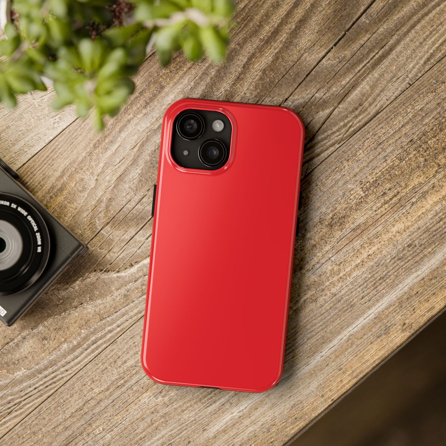 iPhone 15 Aston Martin Volcano Red phone case on a table with accessories. 