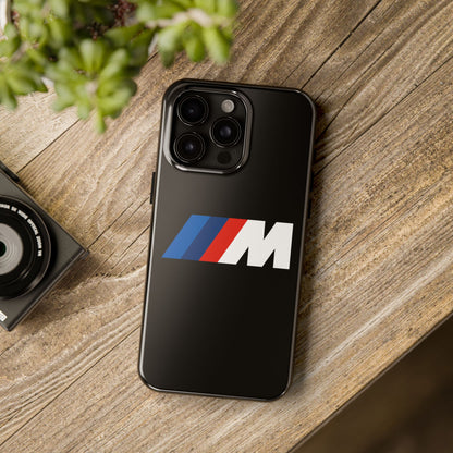 Black iPhone 15 Pro Max BMW M phone case on a table with accessories.