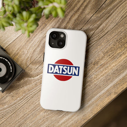 White iPhone 15 Datsun phone case on a table with accessories.