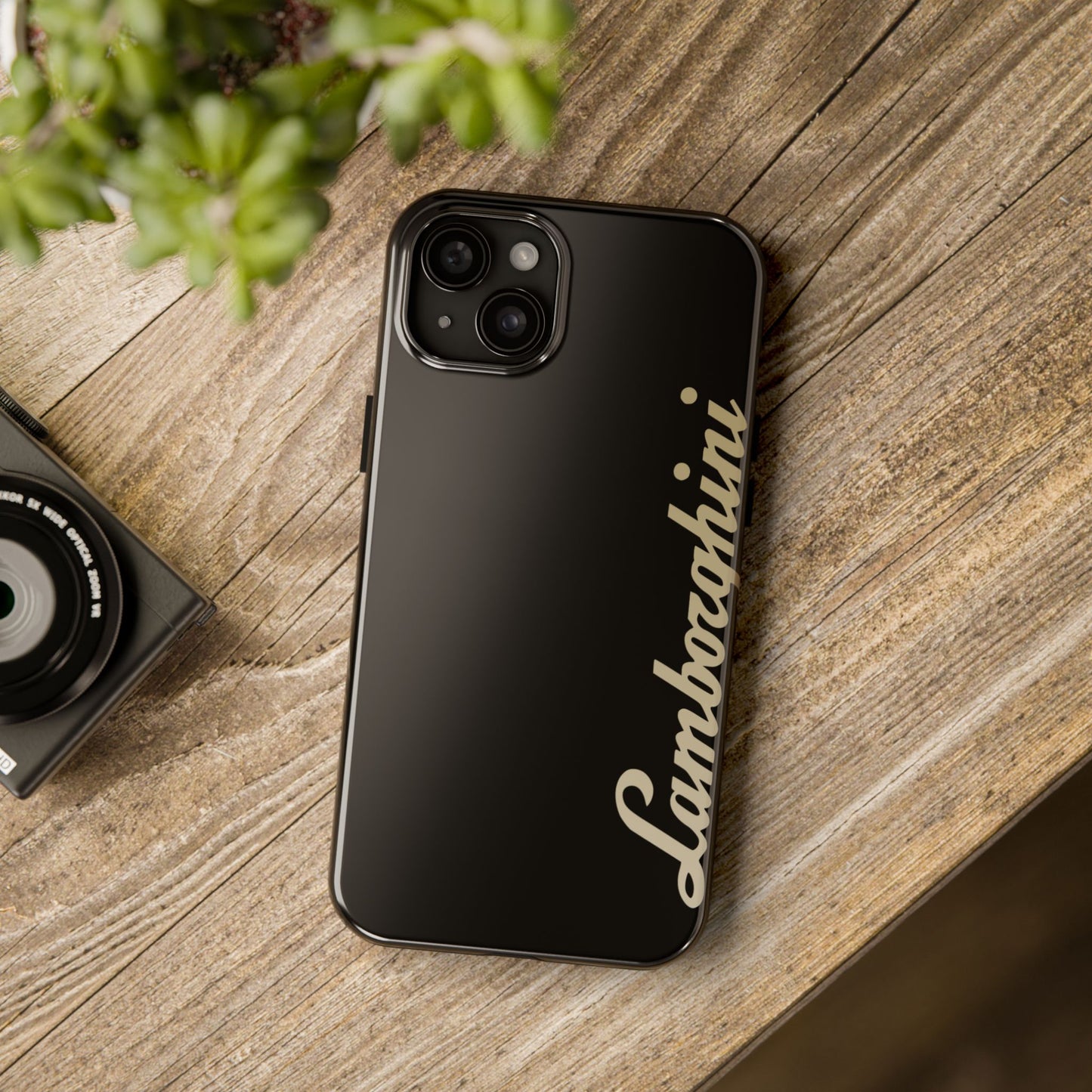 Black iPhone 15 Plus Lamborghini phone case on a table with accessories.