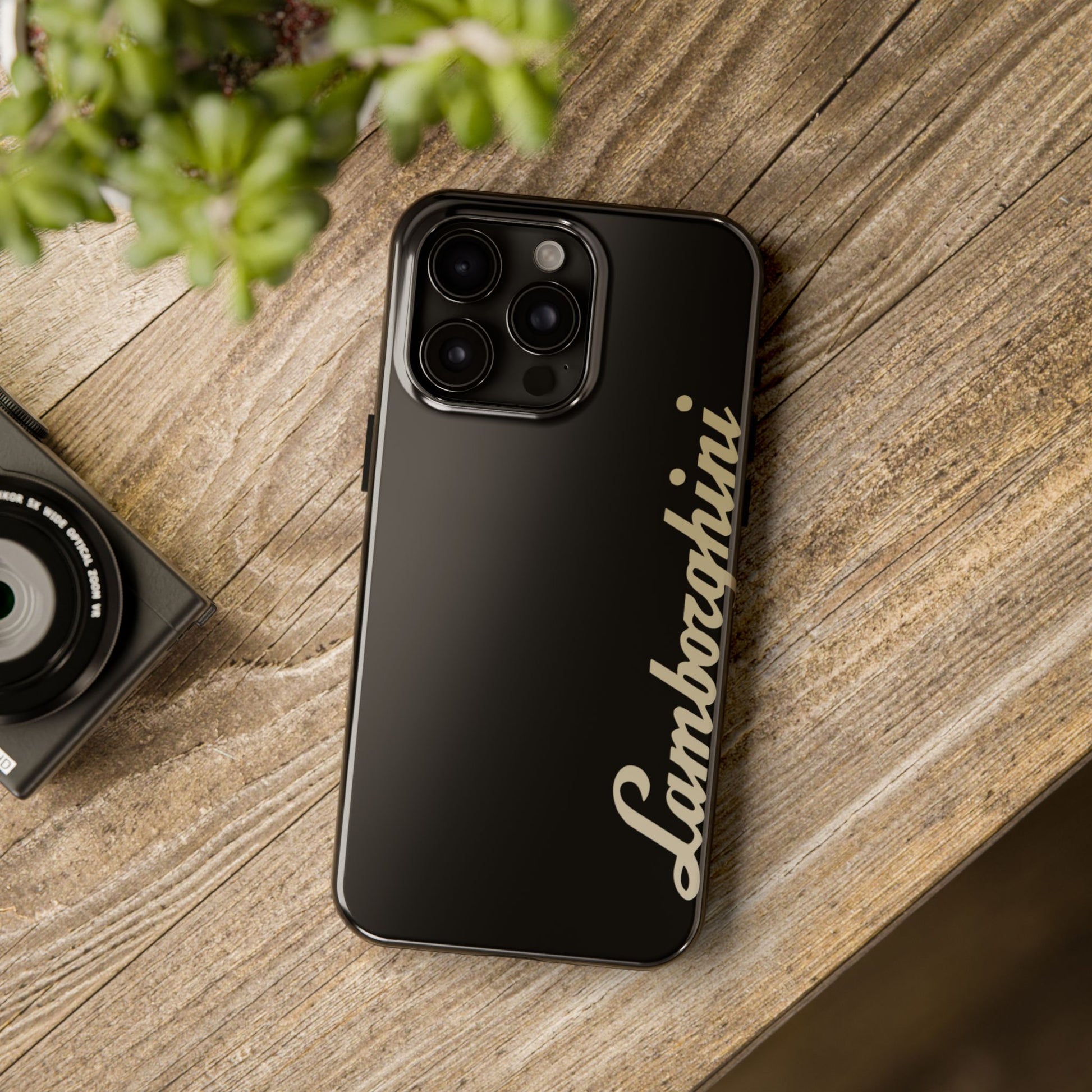 Black iPhone 15 Pro Max Lamborghini phone case on a table with accessories.