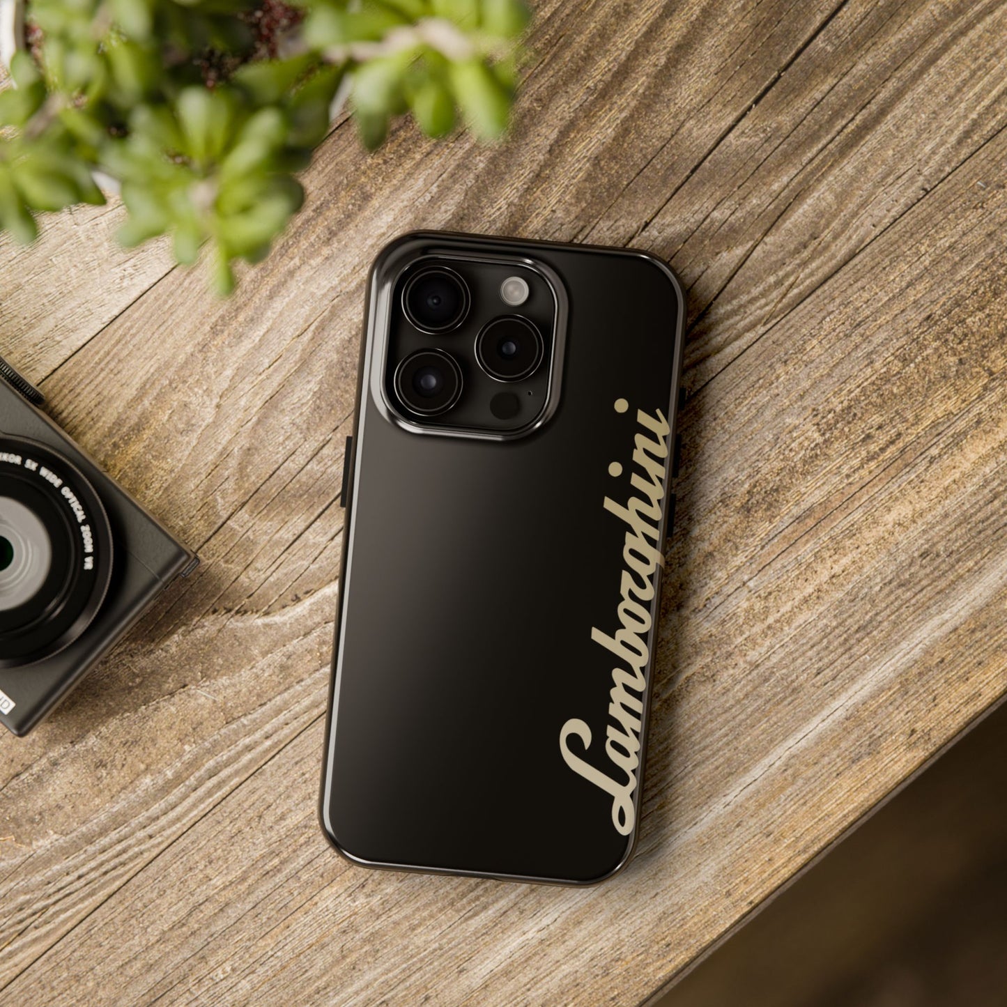 Black iPhone 15 Pro Lamborghini phone case on a table with accessories.