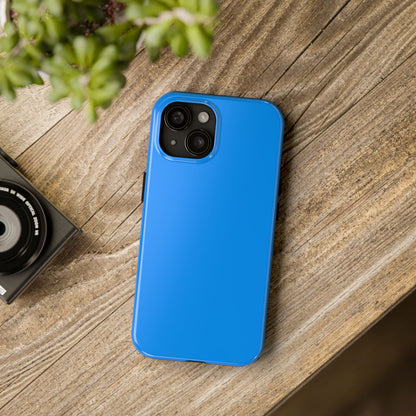 iPhone 15 Porsche Mexico Blue phone case on a table with accessories.