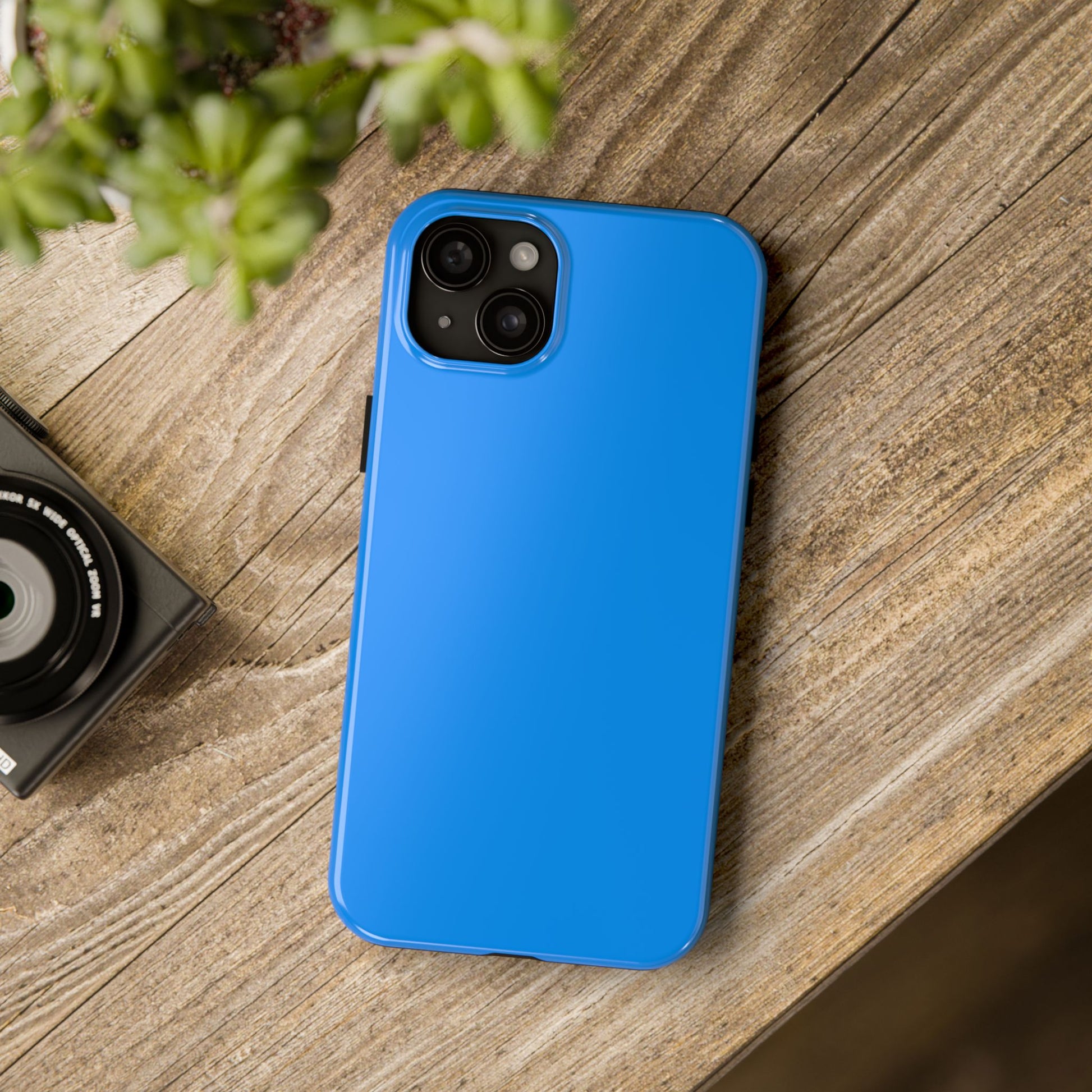 iPhone 15 Plus Porsche Mexico Blue phone case on a table with accessories.