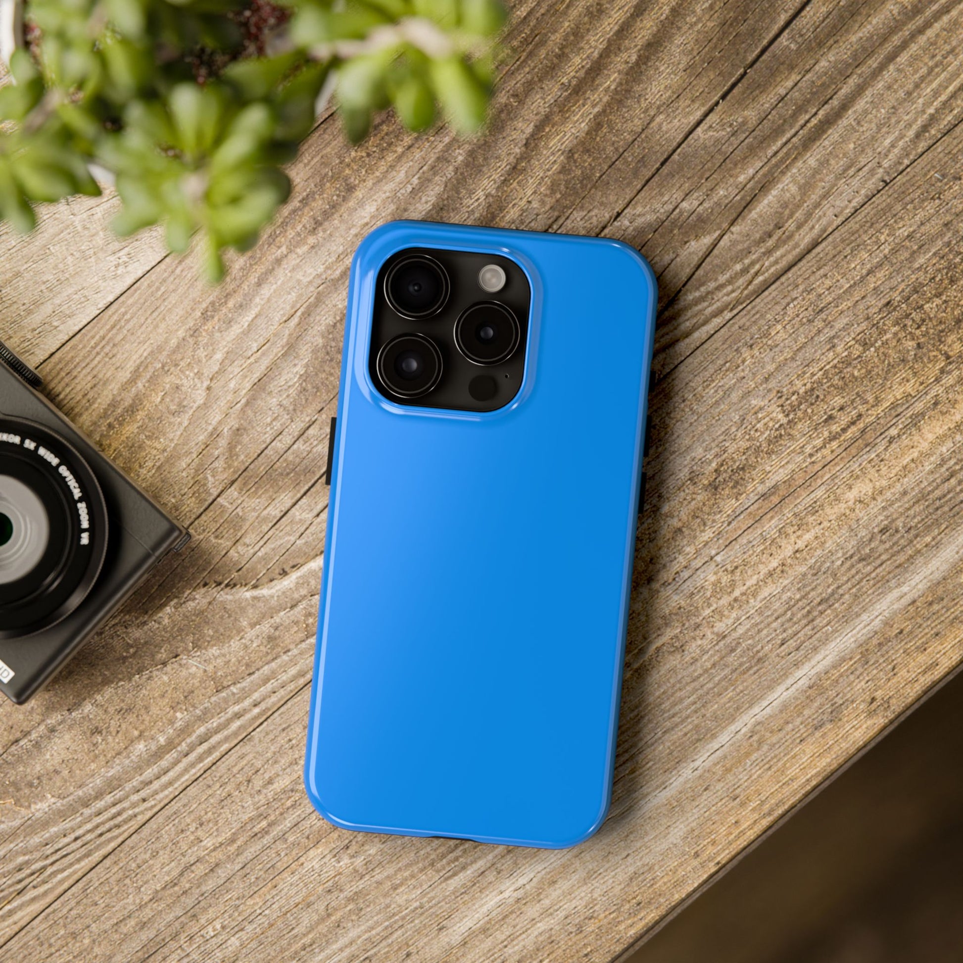 iPhone 15 Pro Porsche Mexico Blue phone case on a table with accessories.