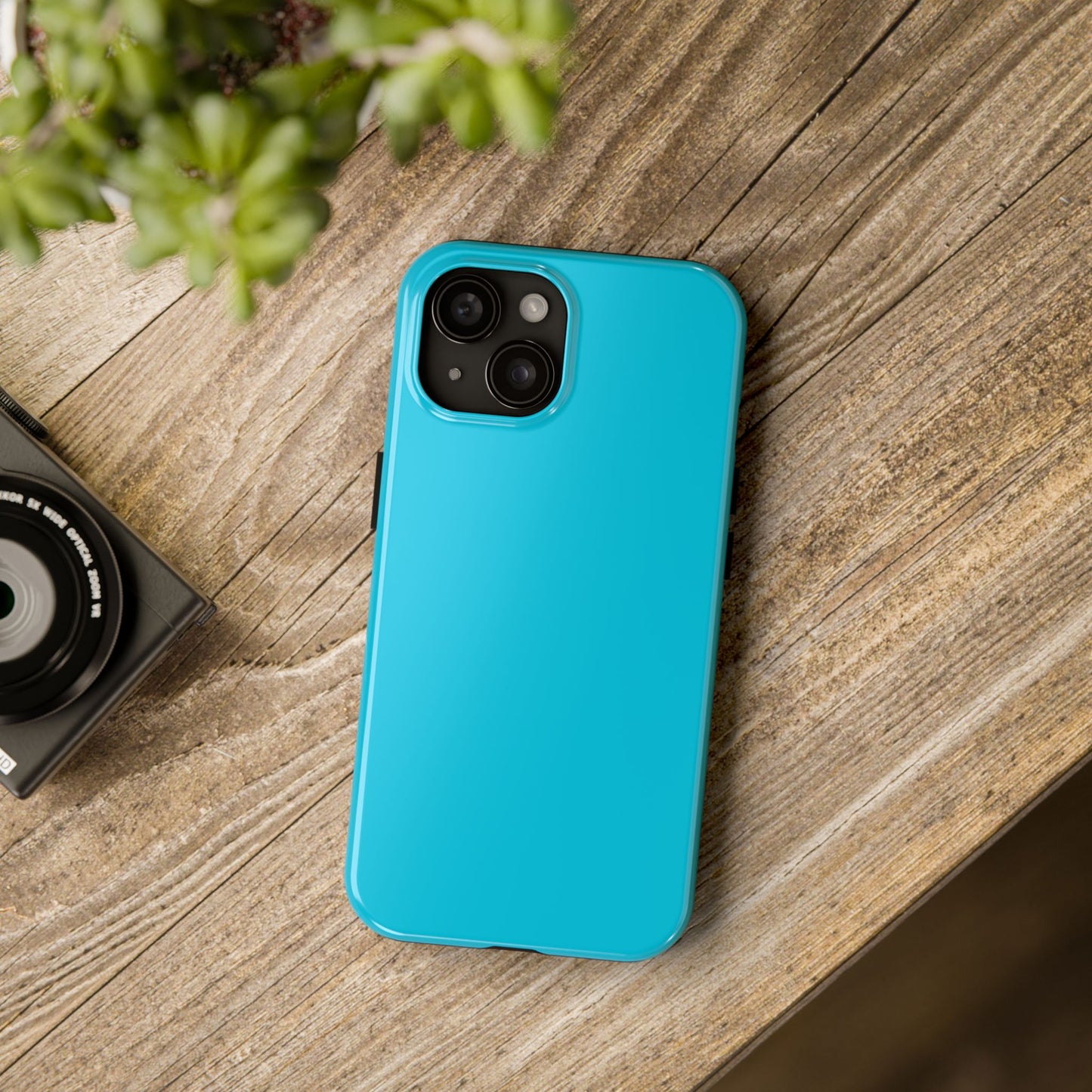 iPhone 15 Porsche Miami Blue phone case on a table with accessories.