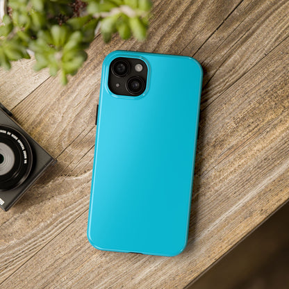 iPhone 15 Plus Porsche Miami Blue phone case on a table with accessories.