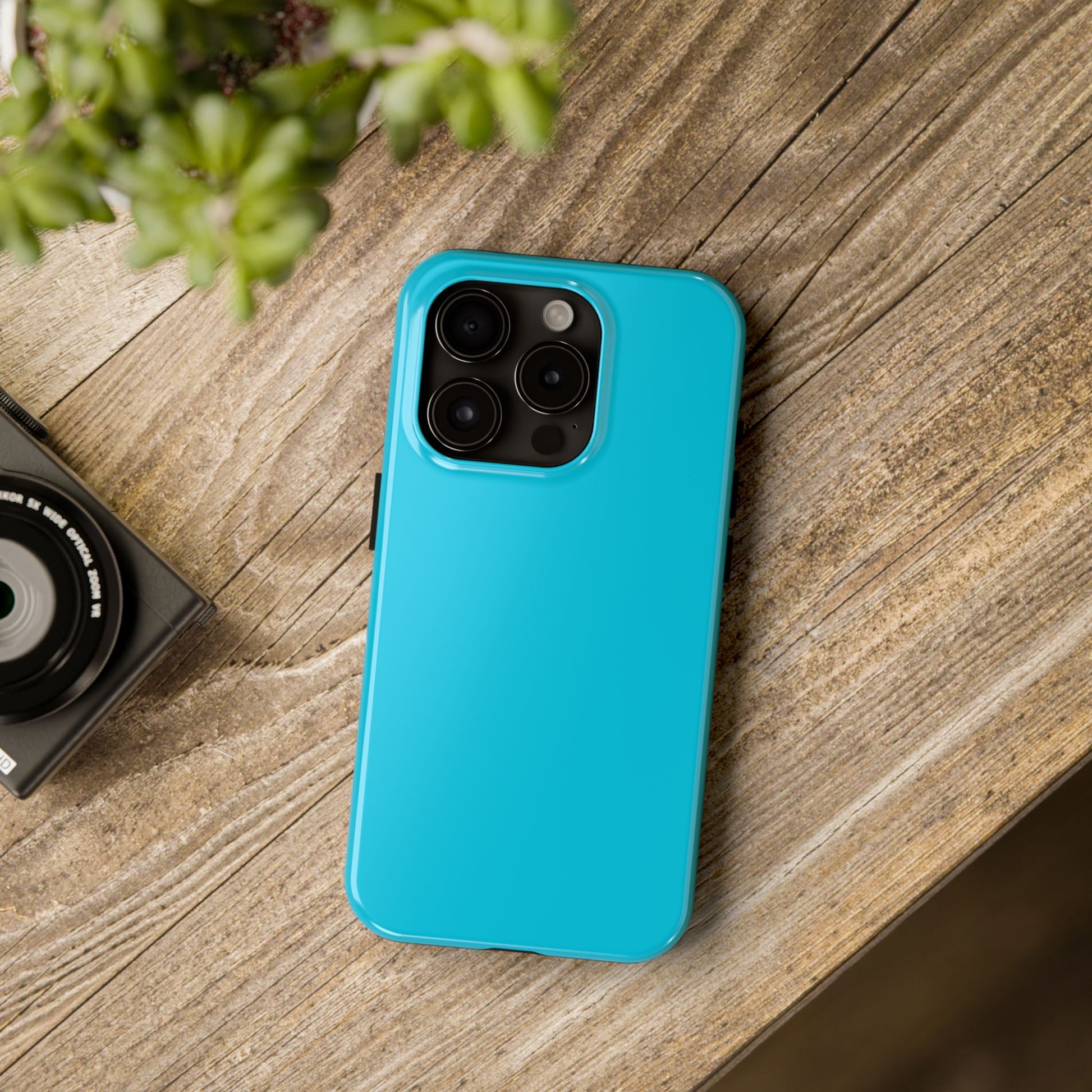 iPhone 15 Pro Porsche Miami Blue phone case on a table with accessories.