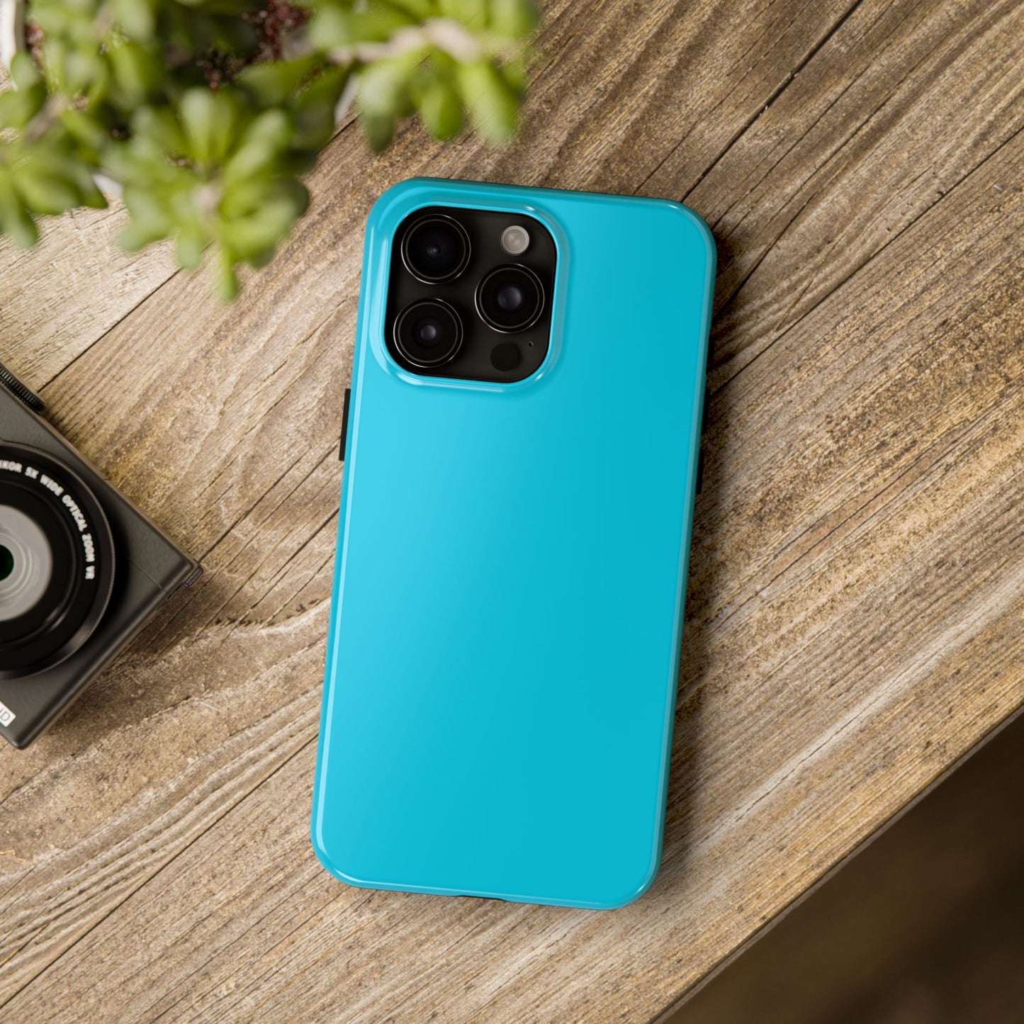 iPhone 15 Pro Max Porsche Miami Blue phone case on a table with accessories.