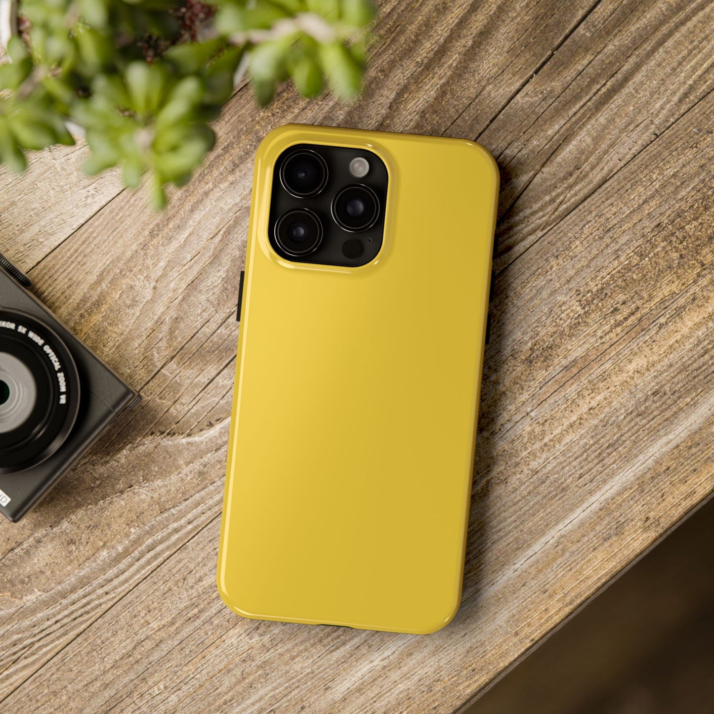 iPhone 15 Pro Max Porsche Speed Yellow phone case on a table with accessories. 