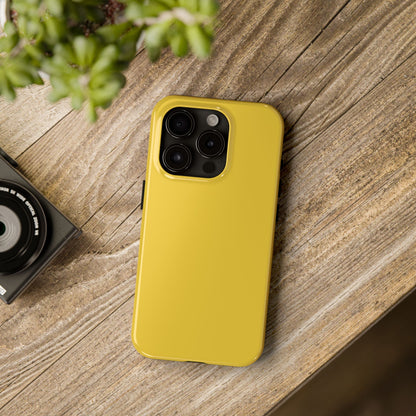 iPhone 15 Pro Porsche Speed Yellow phone case on a table with accessories. 