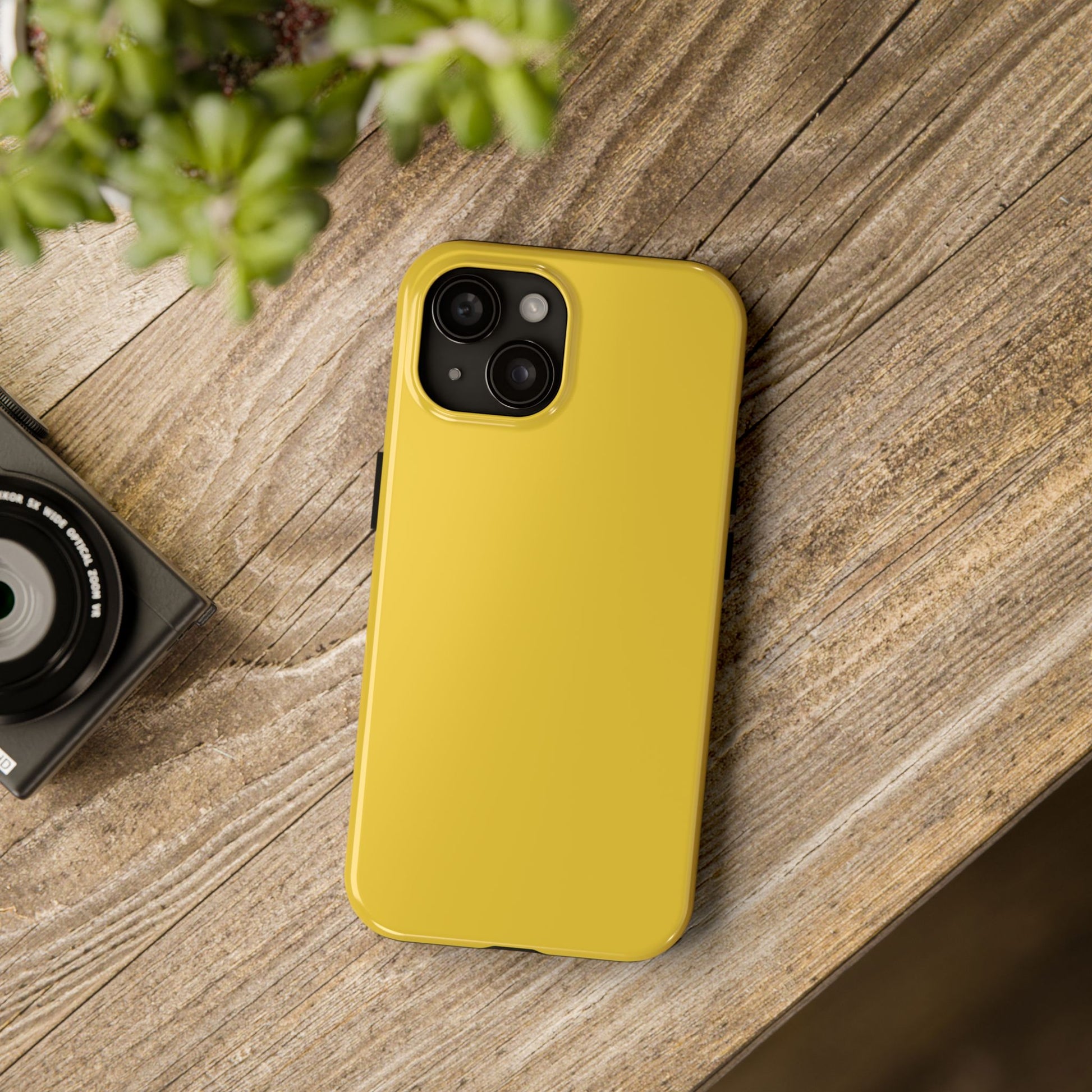 iPhone 15 Porsche Speed Yellow phone case on a table with accessories. 