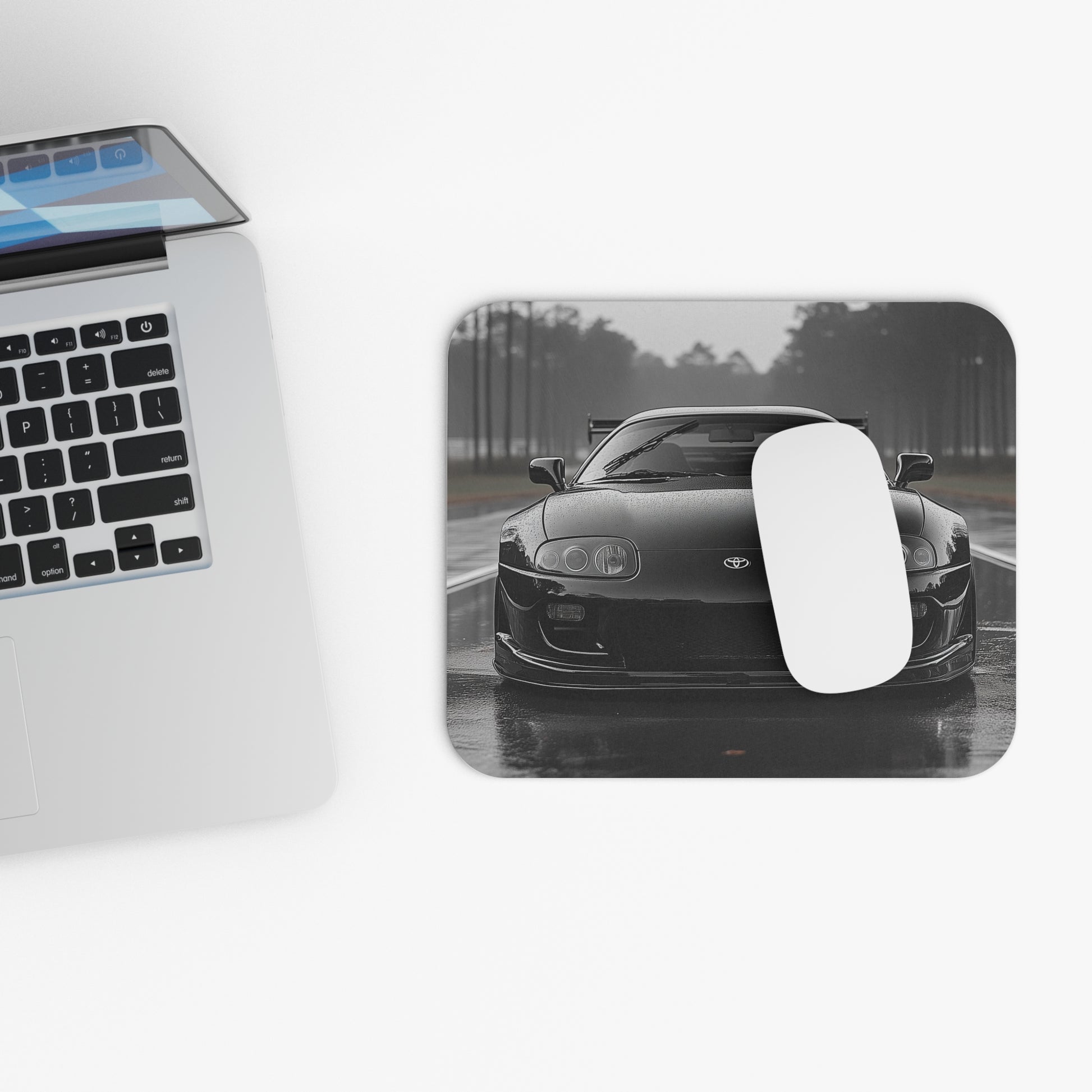 Toyota Supra MK4 mouse pad and mouse placed beside a laptop