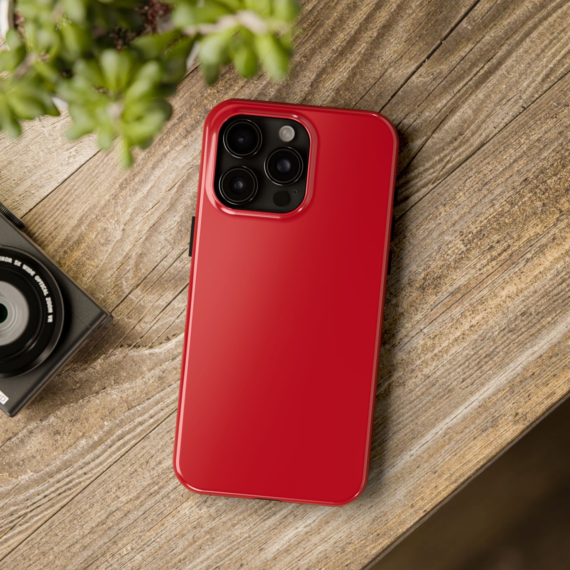 iPhone 15 Pro Max Porsche Guards Red phone case on a table with accessories. 