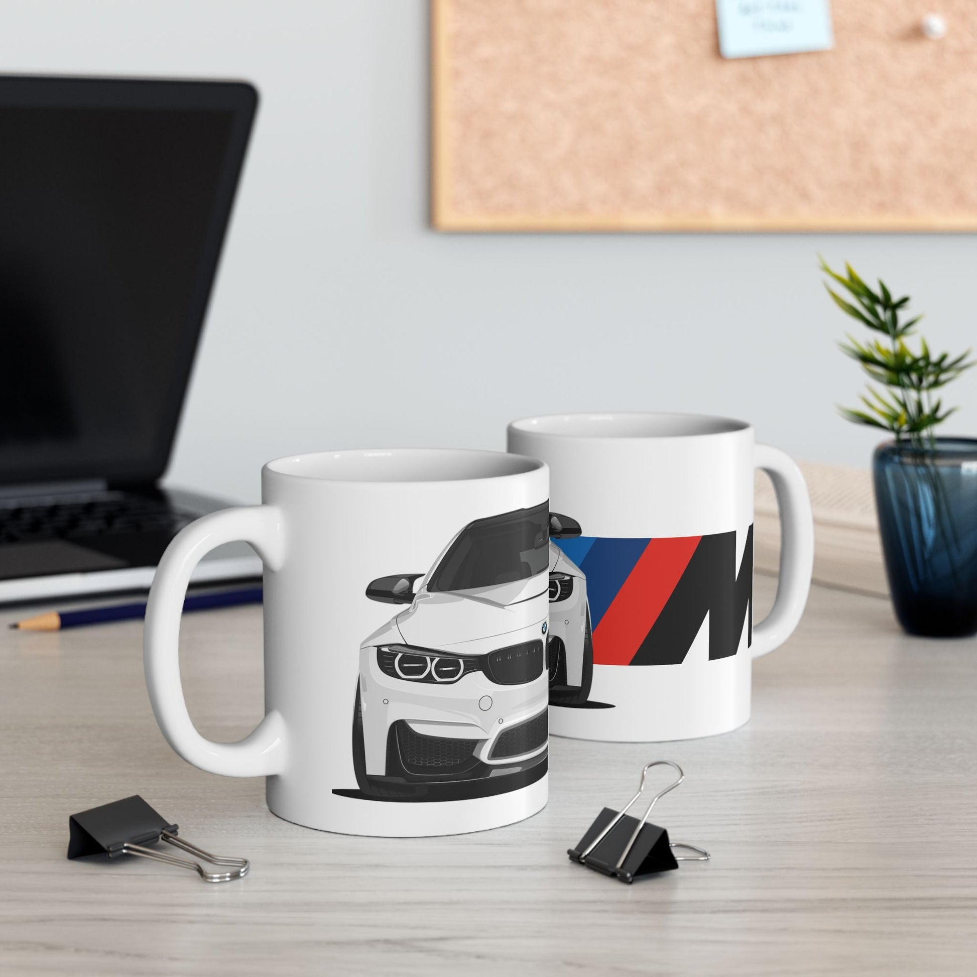 Lifestyle view of the 11oz White Coffee Mug with a White BMW M4 with the M emblem placed behind the car. 